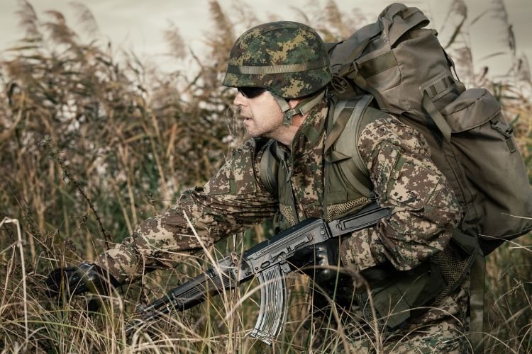 Militare con fucile AK47 in zona con alta vegetazione