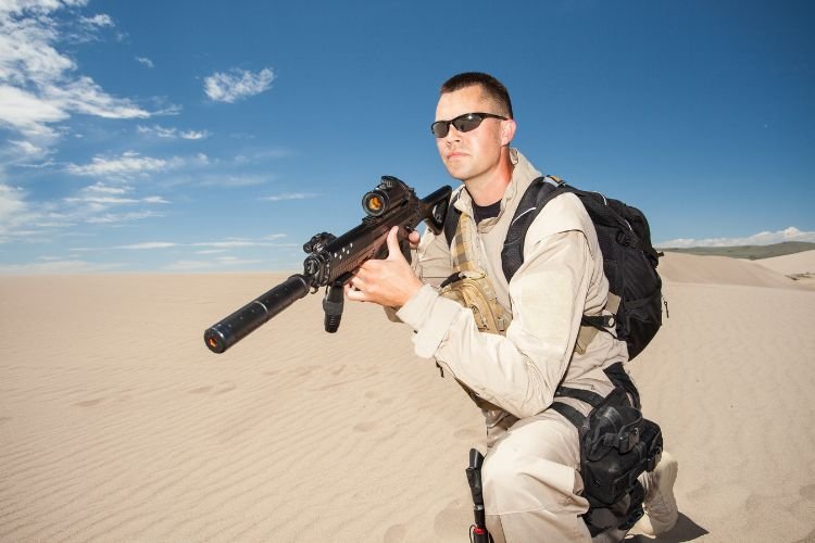 Militare che si appresta a prendere la mira con un fucile da lunga distanza e si trova nel deserto